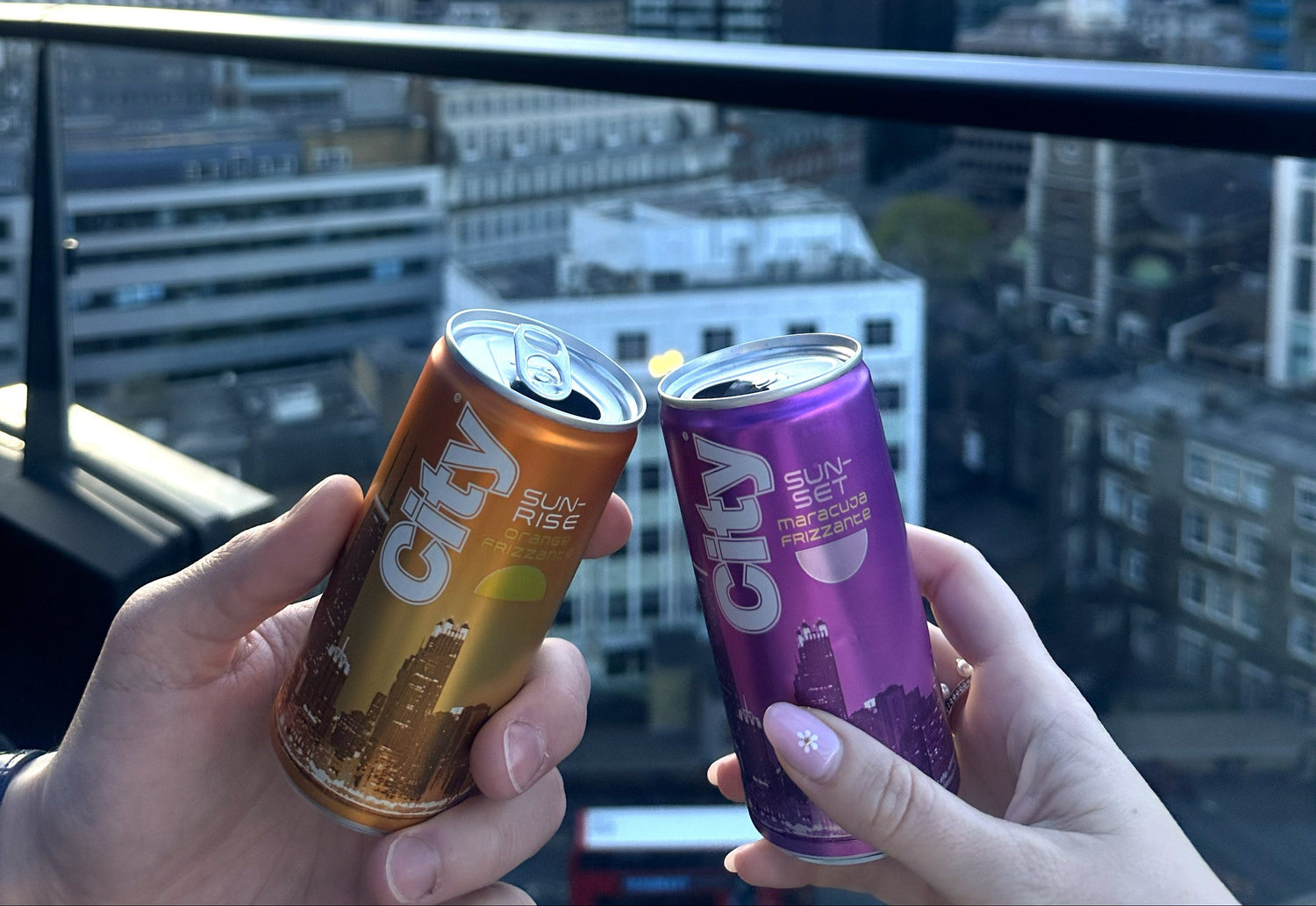 Zwei Dosen, City Sunrise in orange und City Sunset in lila, vor der Skyline von London